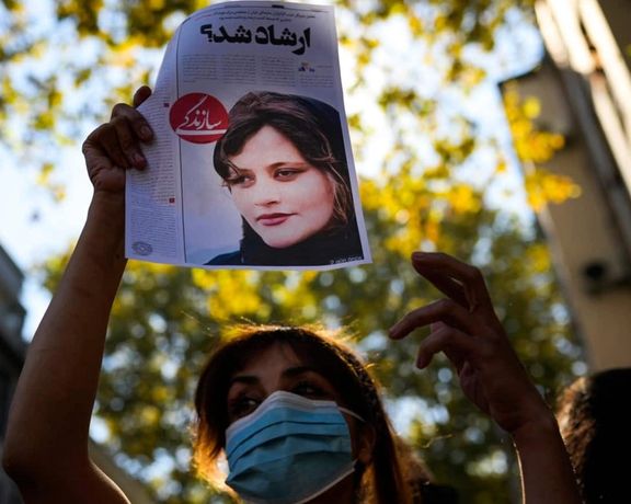 A woman protester in Iran holding a picture of Mahsa Amini who was killed in hijab police custody