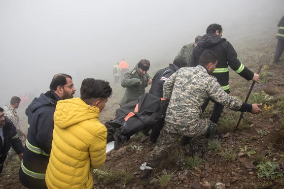 Rescue team members carry the body of a victim Monday at the crash site in Varzaghan, northwestern Iran