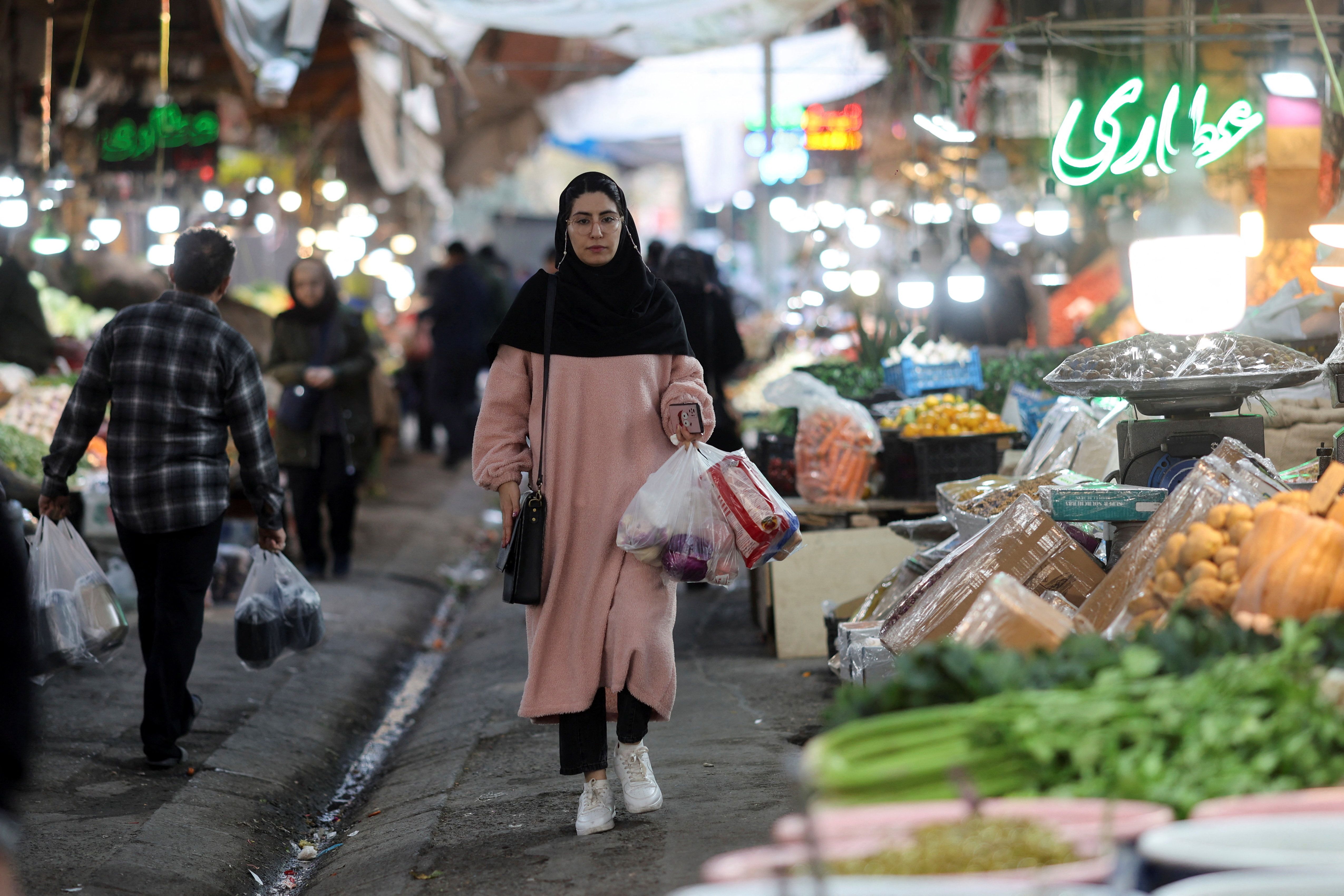 An Iranian woman walks in a local market as the value of the Iranian rial drops, in Tehran, Iran, December 20, 2025. 