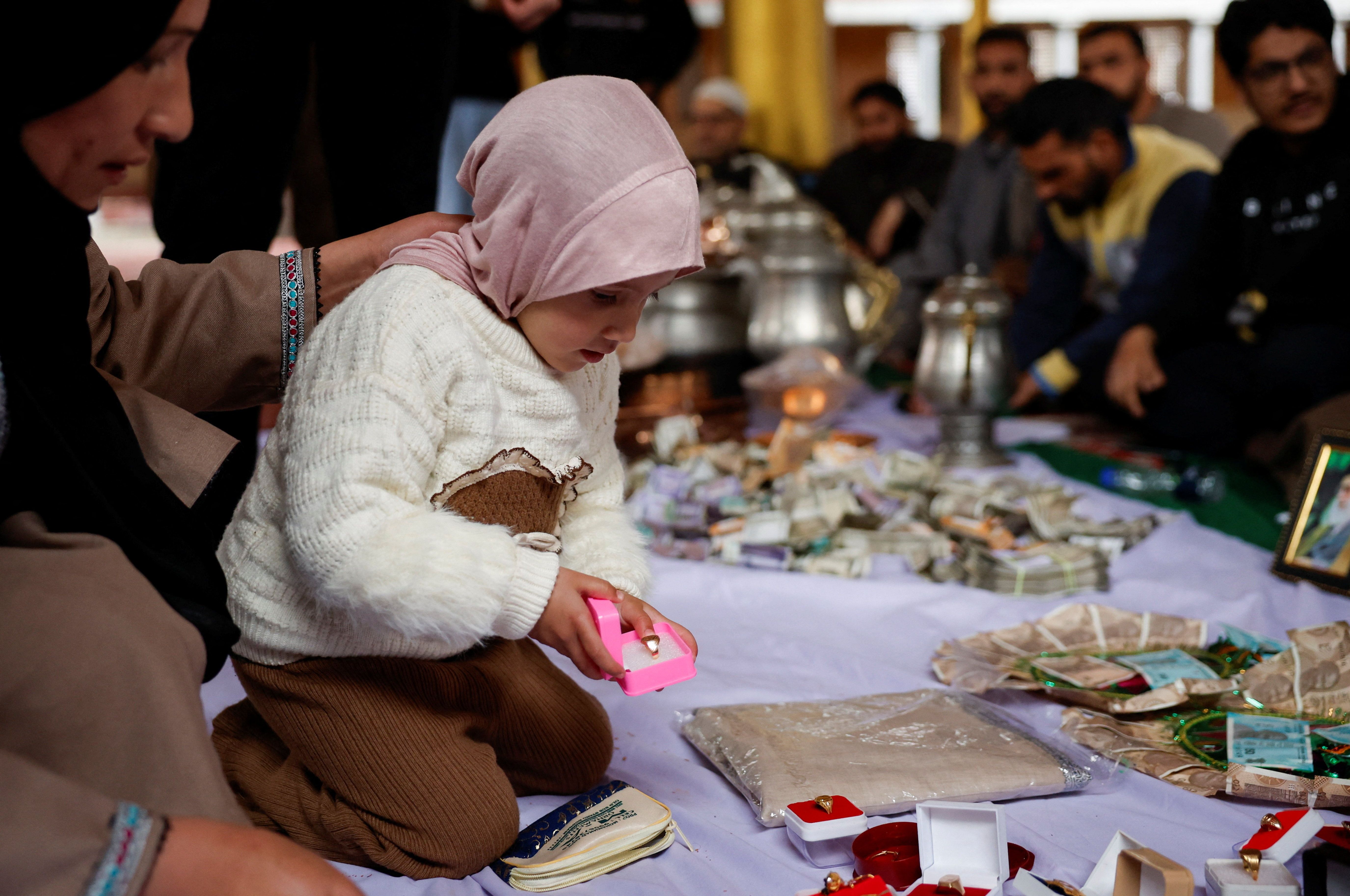 A Kashmiri Muslim girl donates a gold ring at an Imambara fund collection centre in Budgam