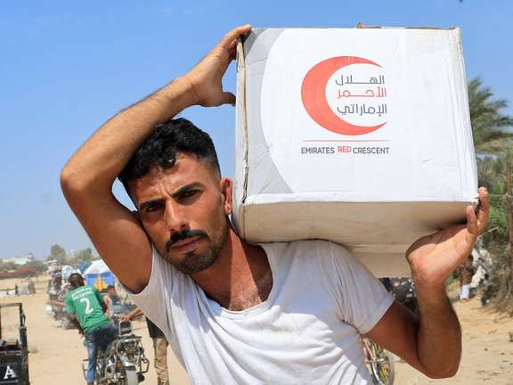 یک فلسطینی بسته مواد غذایی پرتابشده از هواپیما را حمل میکند؛ مرکز نوار غزه، ششم مرداد