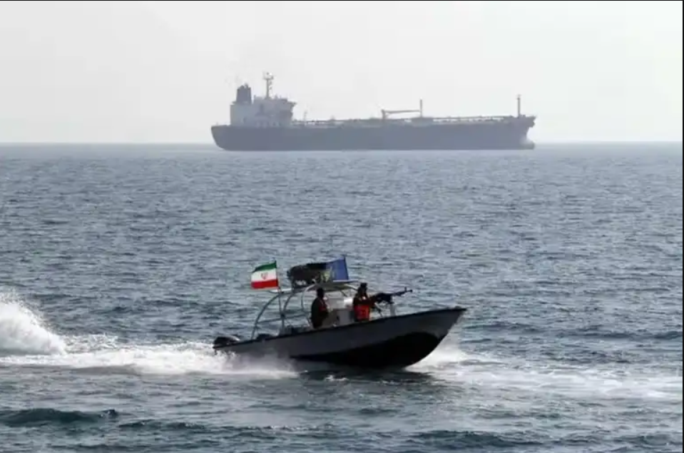 An Iranian patrol boat sails near a commercial tanker in the Strait of Hormuz