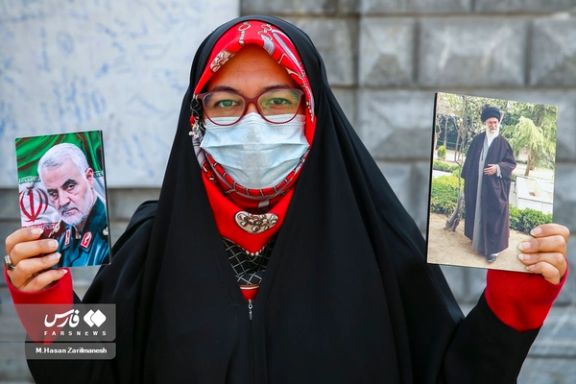 A pro-regime woman holding photos of Iran’s ruler Ali Khamenei and Qassem Soleimani, the former commander of IRGC's extraterritorial Quds Force who was killed by the US in 2020, Tehran