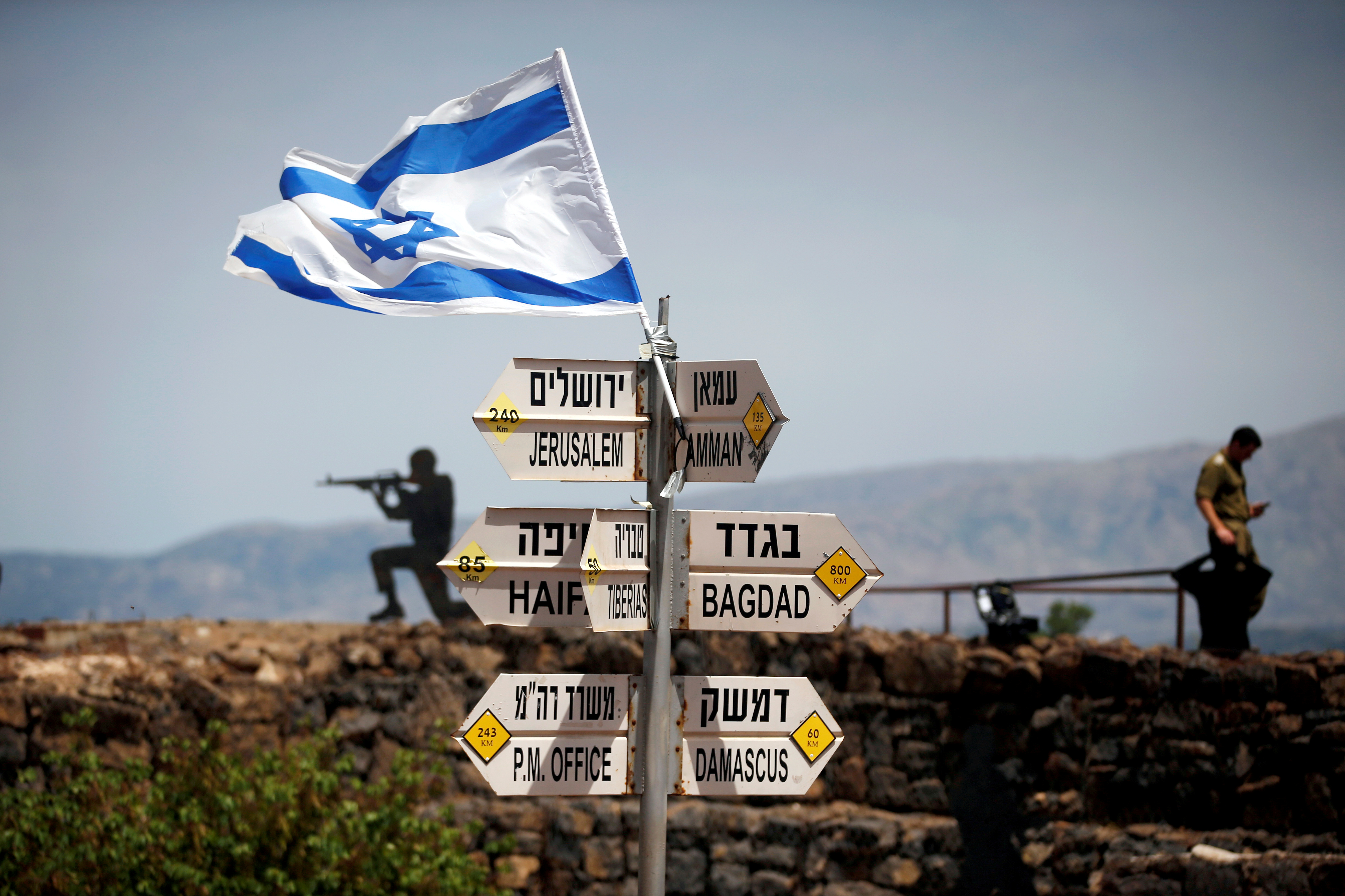 An Israeli soldier stands next to signs pointing out distances to different cities, on Mount Bental, an observation post in the Israeli-occupied Golan Heights that overlooks the Syrian side of the Quneitra crossing, Israel May 10, 2018. 