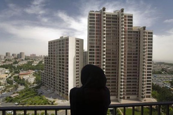 A woman rests at her apartment's balcony in a residential building in northwestern Tehran