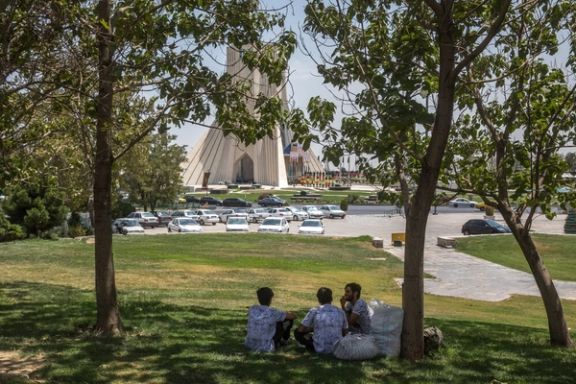 سه مرد نشسته در سایه درختی در نزدیکی میدان آزاد تهران ، ایران ، 19 ژوئیه 2025