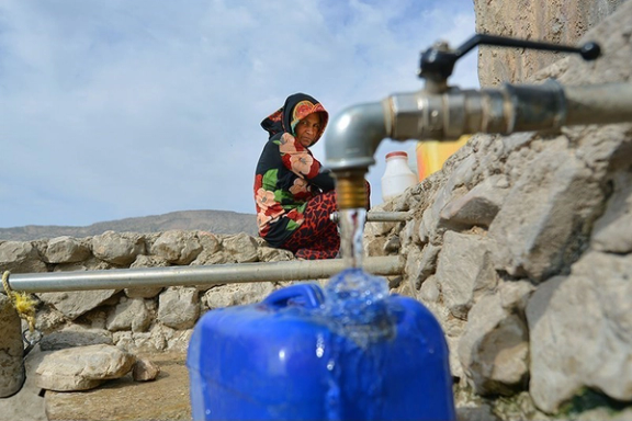 A young girl carries containers to collect water from a tanker truck amid ongoing shortages in Iran.