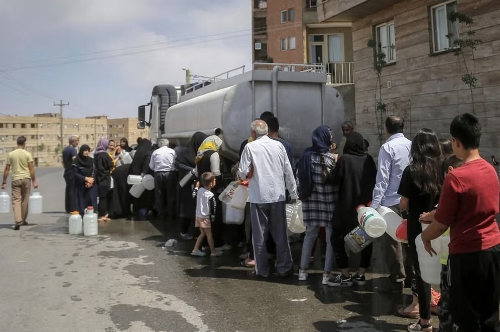 File photo shows residents lining up with containers to collect water from a tanker truck during water shortages in Iran.