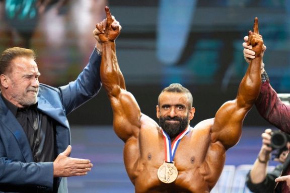 Arnold Schwarzenegger, a dominant figure in the bodybuilding industry, raising the hand of Iranian bodybuilder Hadi Choopan after he won the first place in the Arnold Classic Bodybuilding, Ohio, the US (March 2024)