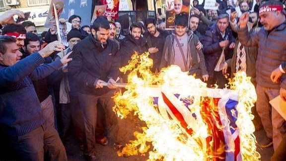 Pro-regime demonstrators burning the UK flag during a government-sponsored rally