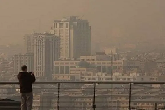 A man looks out over Tehran during heavy fog, December 2025