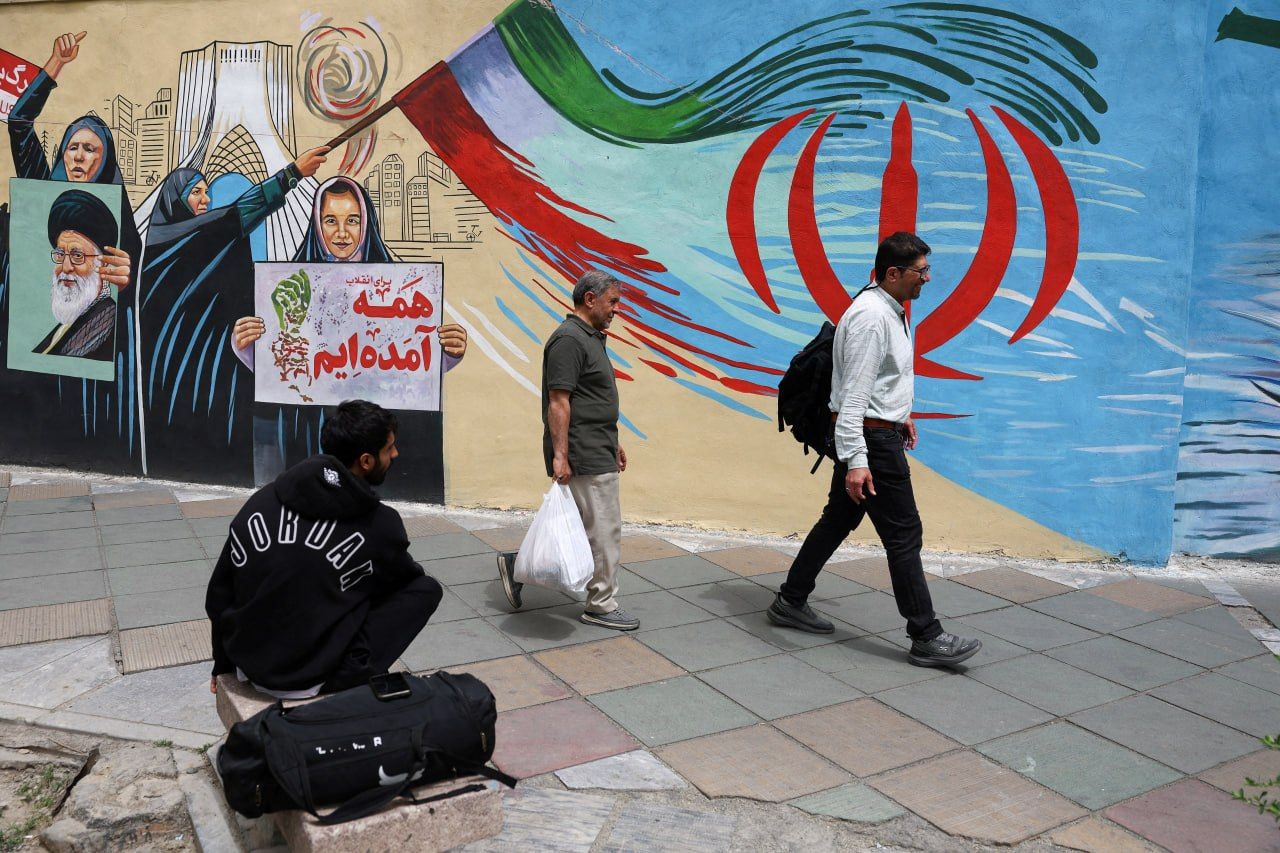 People walk past a mural featuring the Islamic Republic flag in Tehran, Iran, May 5, 2026.