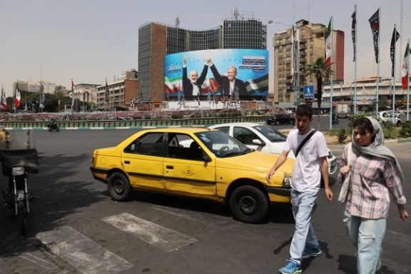 People walk past a billboard with a picture of assassinated Hamas chief Ismail Haniyeh and Iran's President, Masoud Pezeshkian, in a street in Tehran, Iran, August 1, 2024.