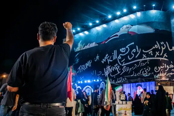 A man gestures toward a giant anti-Trump billboard during a nightly state-backed rally in Tehran, July, 25, 2026