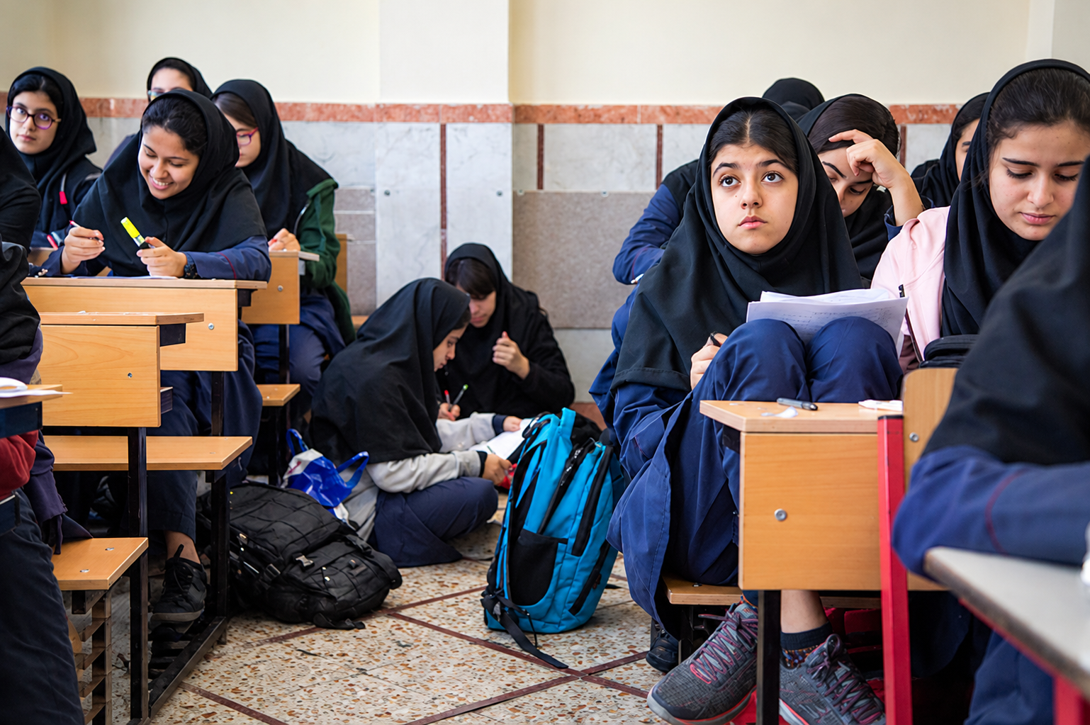 Female students attend a classroom lesson at a school in Iran, where the education system emphasizes Islamic values and a centrally prescribed curriculum.