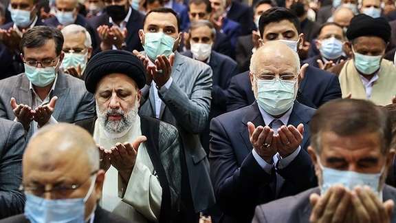 President Ebrahim Raisi praying with members of parliament in April 2022