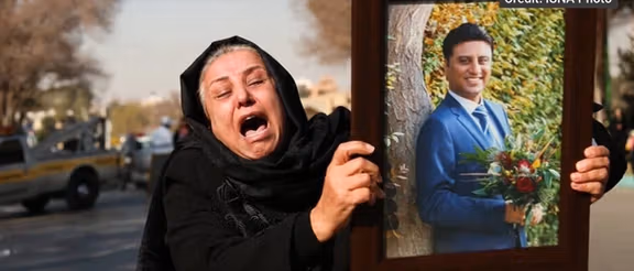 Mehran Abtahi's mother in Iran holding a photo of her son.
