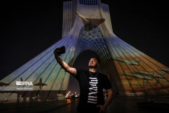 A man is taking a selfie in front of Tehran’s Azadi tower as photos of Iran’s missiles and drones are projected on it to celebrate Tehran’s attack on Israel (April 2024)