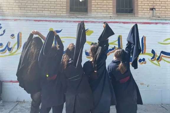 Several students unveiling at their schoolyard in protest to mandatory hijab