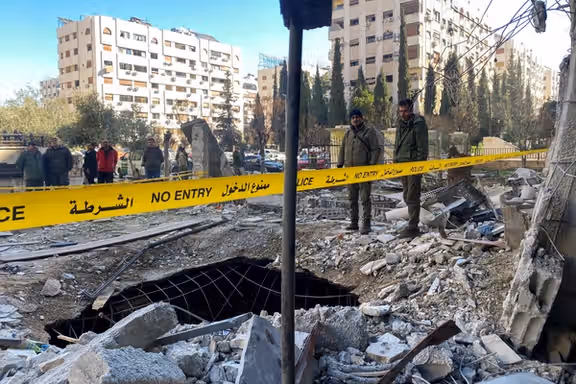 Police officers stand amid the rubble of a damaged building at the site of a rocket attack in the Kafr Sousa neighbourhood of central Damascus, Syria, February 19, 2023