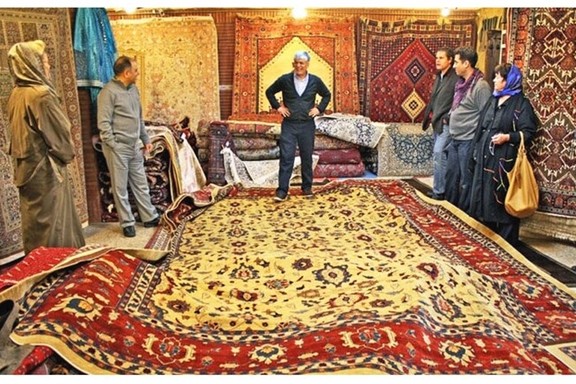 A carpet seller displays inventory to buyers in Tehran