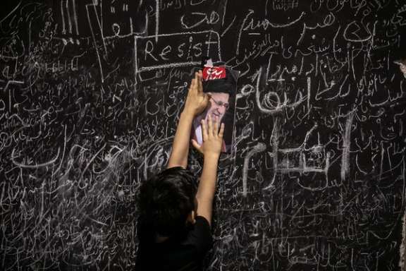 A child places a picture of Ali Khamenei among handwritten messages left by mourners on a memorial wall set up during funeral ceremonies in Tehran, July 5, 2026