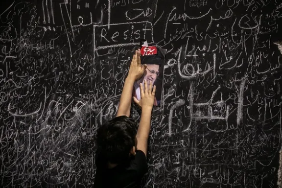 A child places a picture of Ali Khamenei among handwritten messages left by mourners on a memorial wall set up during funeral ceremonies in Tehran, July 5, 2026
