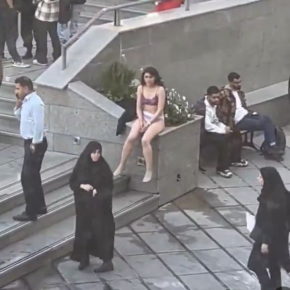 A screenshot from the video shows the female student sitting disrobed on Tehran's Azad University campus.