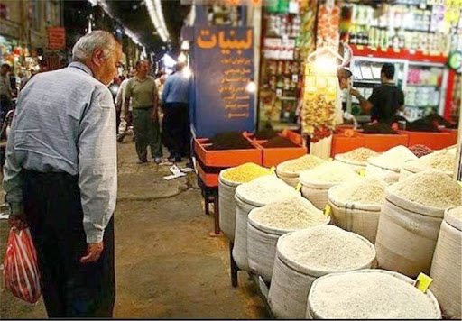 An elderly man checking rice prices at a market in Iran
