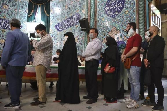 Several Iranians standing in line to cast their votes in an election