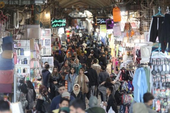 Two women without hijab walk past a building in Tehran displaying a large mural with the slogan "Death to America".