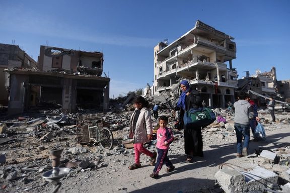 Displaced Palestinians return to their homes as they walk near houses destroyed in an Israeli strike in Khan Younis in the southern Gaza Strip November 24, 2023.