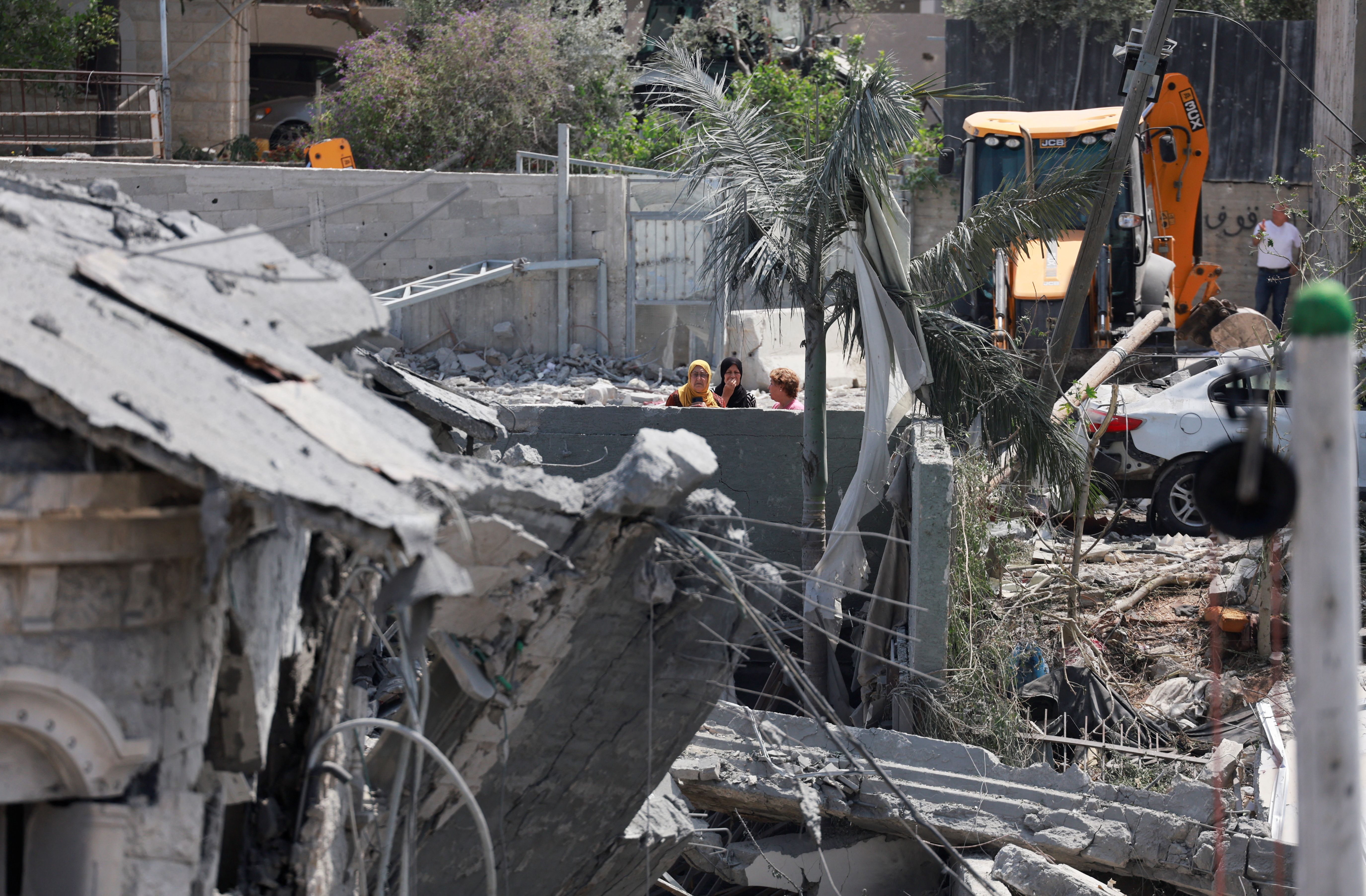 Women look at a damaged building and debris after missiles fired from Iran impacted a residential building, in Tamra, northern Israel June 15, 2025.