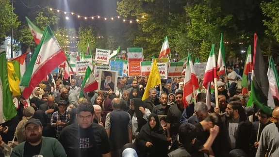 Supporters of the Islamic Republic attend a pro-government rally, waving flags and holding portraits of former Supreme Leader Ali Khamenei.