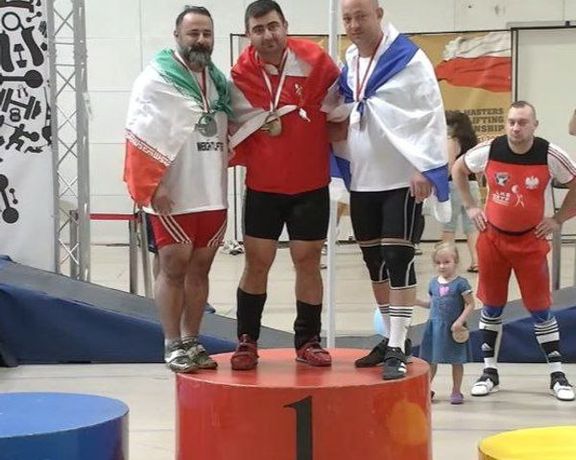 Weightlifter Mostafa Rajai Langroudi posing for a photograph with an Israeli athlete at the World Master Weightlifting Championships in Poland