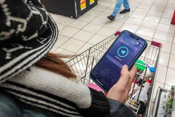 A woman checks her mobile phone while shopping in this file photo
