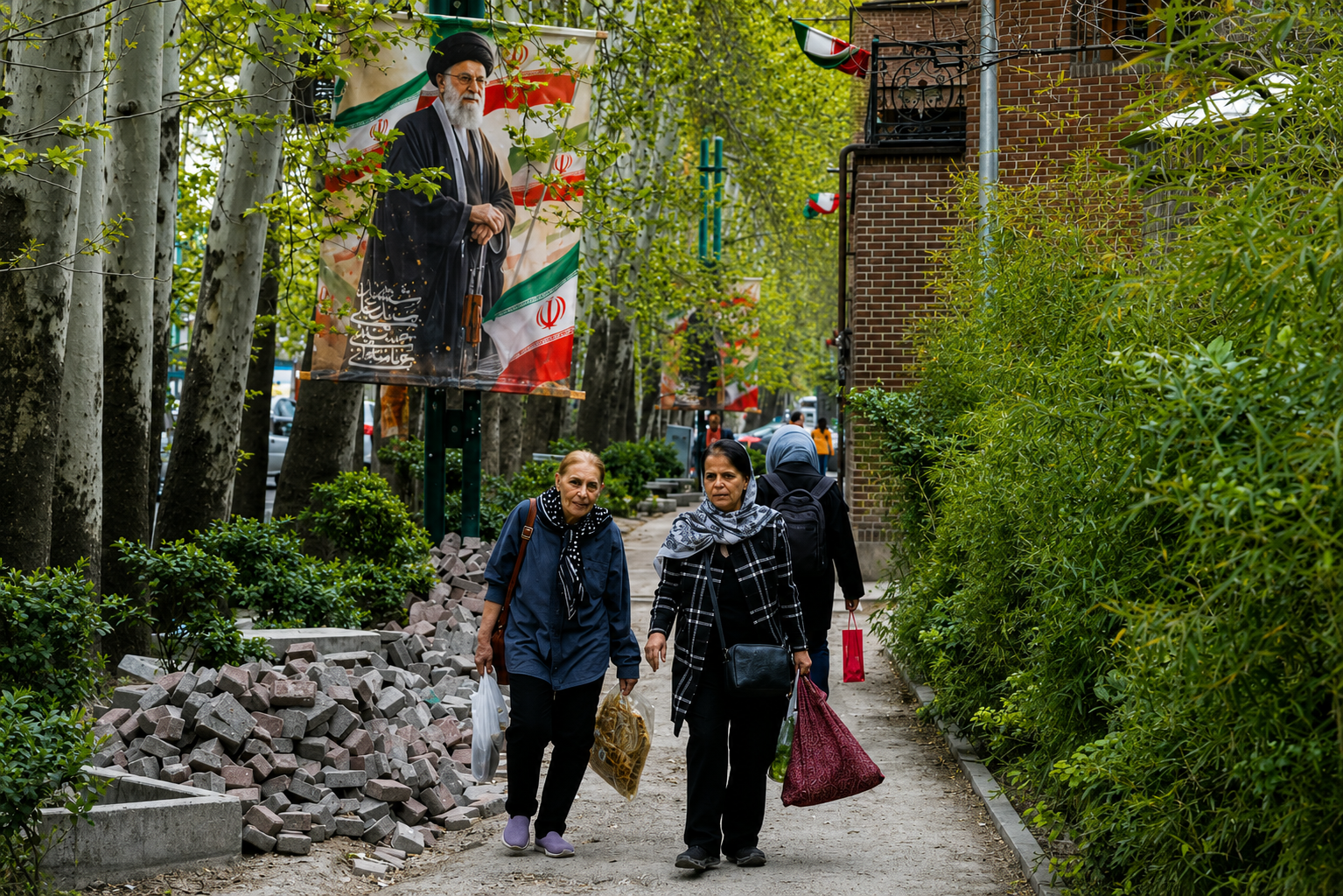 Women walk past a Khamenei street banner in Tehran as inflation and rising living costs continue to strain household budgets in Iran.