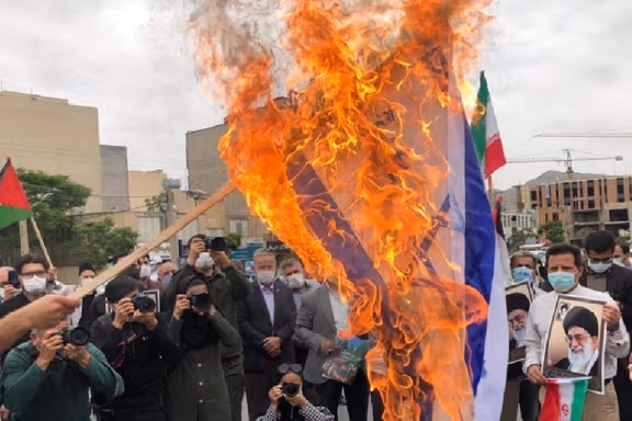 Protesters in Iran burn an Israeli flag