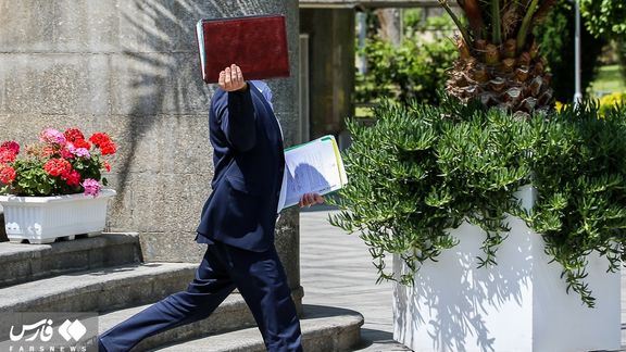 One of the participants in a cabinet meeting of Ebahim Rasis’s administration covering his face as he leaves the session