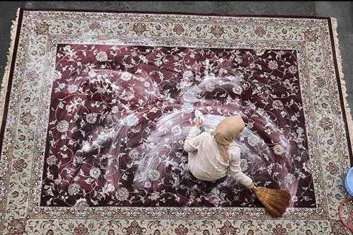 An Iranian person washes a carpet during traditional spring cleaning, known as khaneh-Tekani, ahead of the Nowruz new year celebrations.