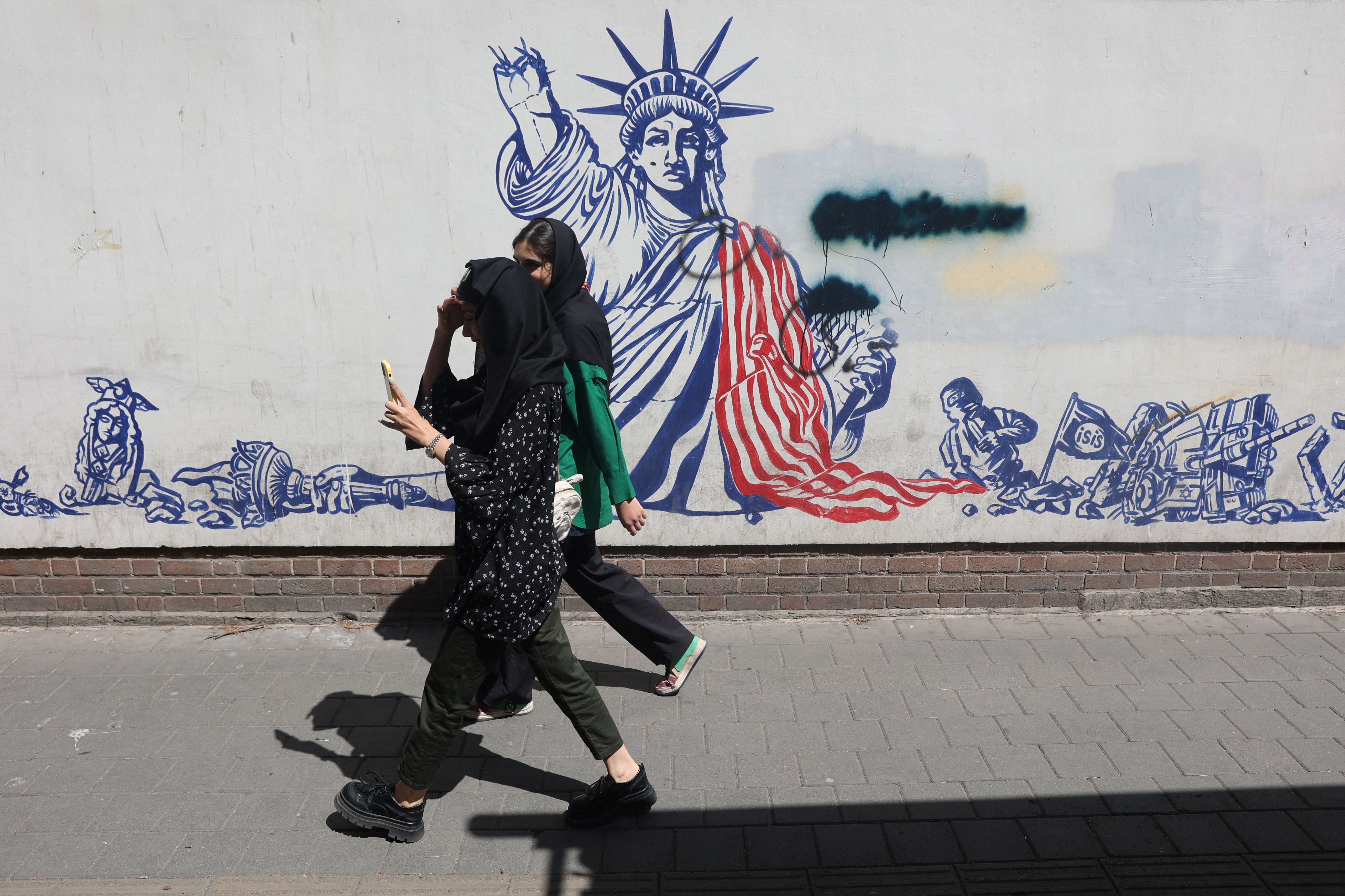 People walk past an anti-US mural on a street in Tehran, Iran, April 19, 2025.