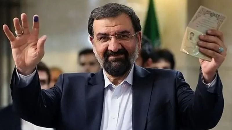 Mohsen Rezaei shows his identification after registering to run in Iran’s presidential election.