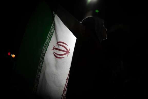 Silhouette of a women carrying an Iranian flag during a state-sponsored rally in Tehran, May 18, 2026