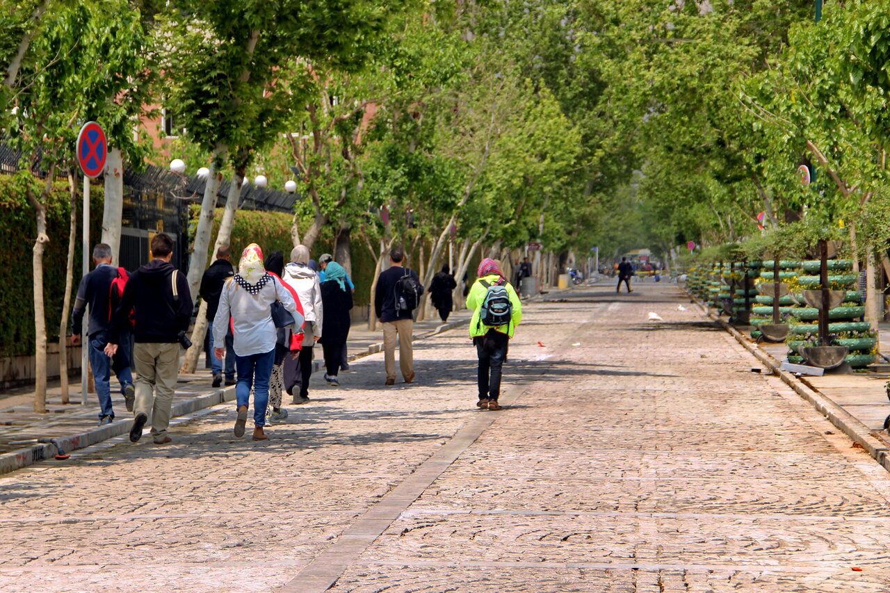 Pedestrians stroll along a cobblestone walkway in central Tehran.