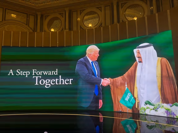 A screen displays a picture of Saudi Arabia's King Salman bin Abdulaziz Al-Saud shaking the hand of U.S. President Donald Trump at the Saudi-U.S. Investment Forum 2025 in Ritz Carlton Hotel, ahead of the arrival of the US President, in Riyadh, Saudi Arabia, May 13, 2025.