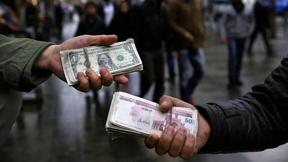 Money changers holding Iranian rial and US dollar banknotes in Tehran's business district  