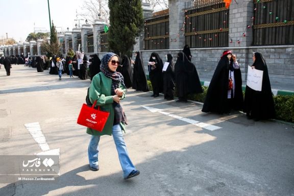 An Iranian woman walks past a group of pro-regime demonstrators in Tehran.