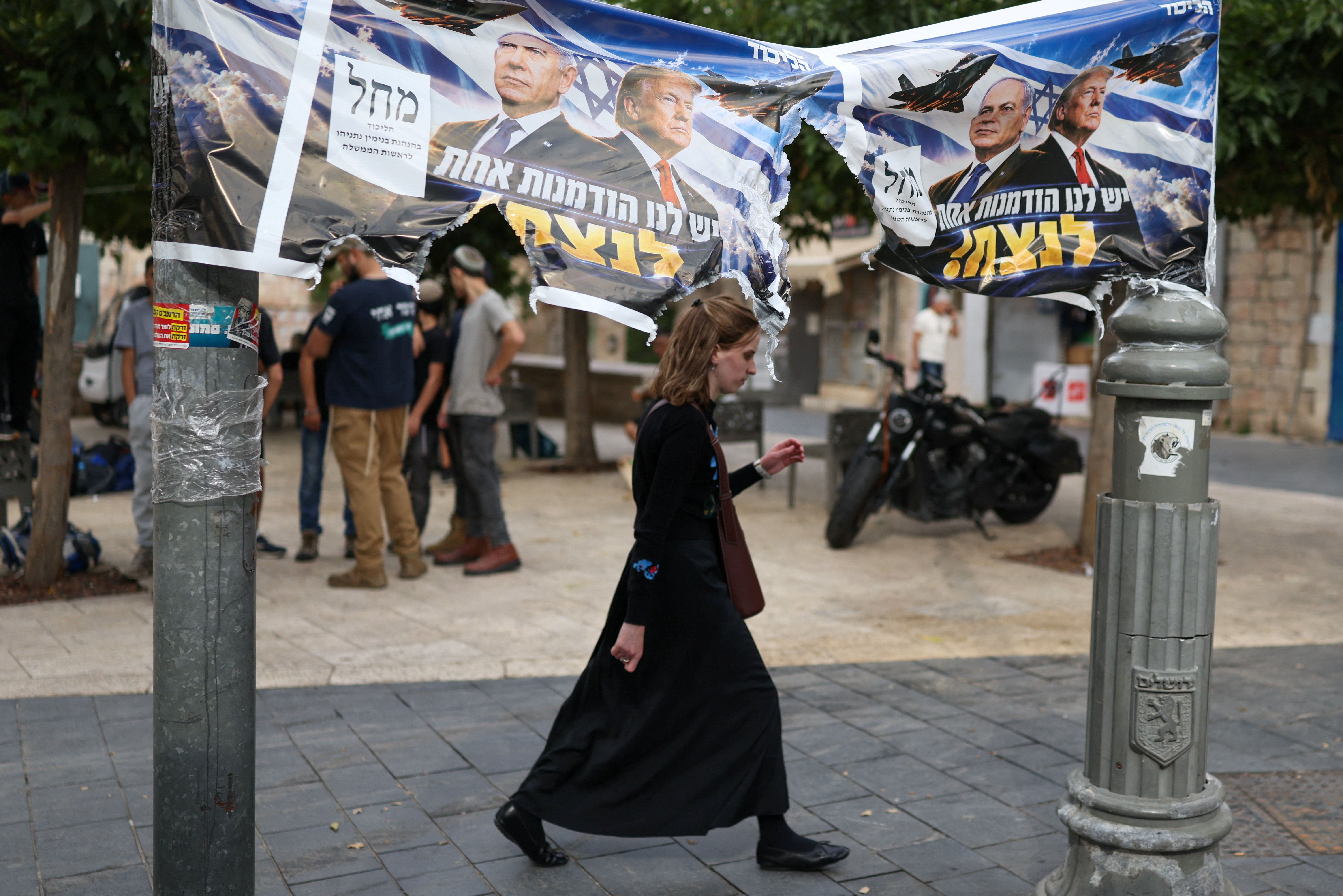 A woman passes by a banner depicting Israeli Prime Minister Benjamin Netanyahu and US President Donald Trump day after the country held a national election, in Jerusalem, October 28 , 2026. 